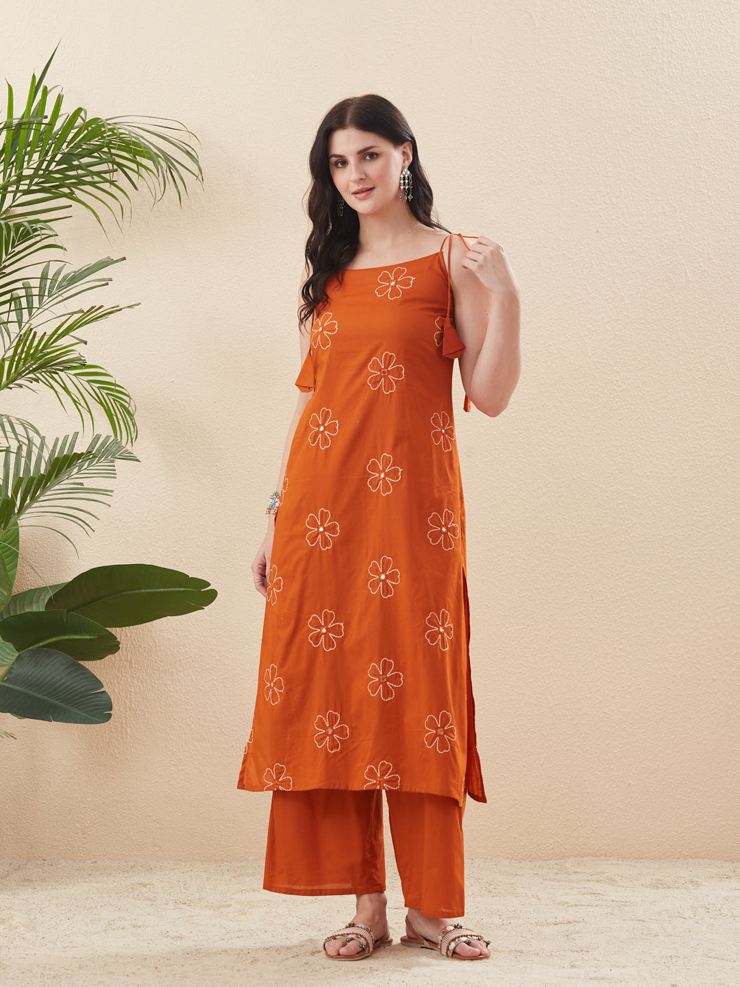 Woman wearing an orange embroidered outfit standing next to a plant on a beige background Orange Cotton Embroidered Kurta with Palazzo Set for Women