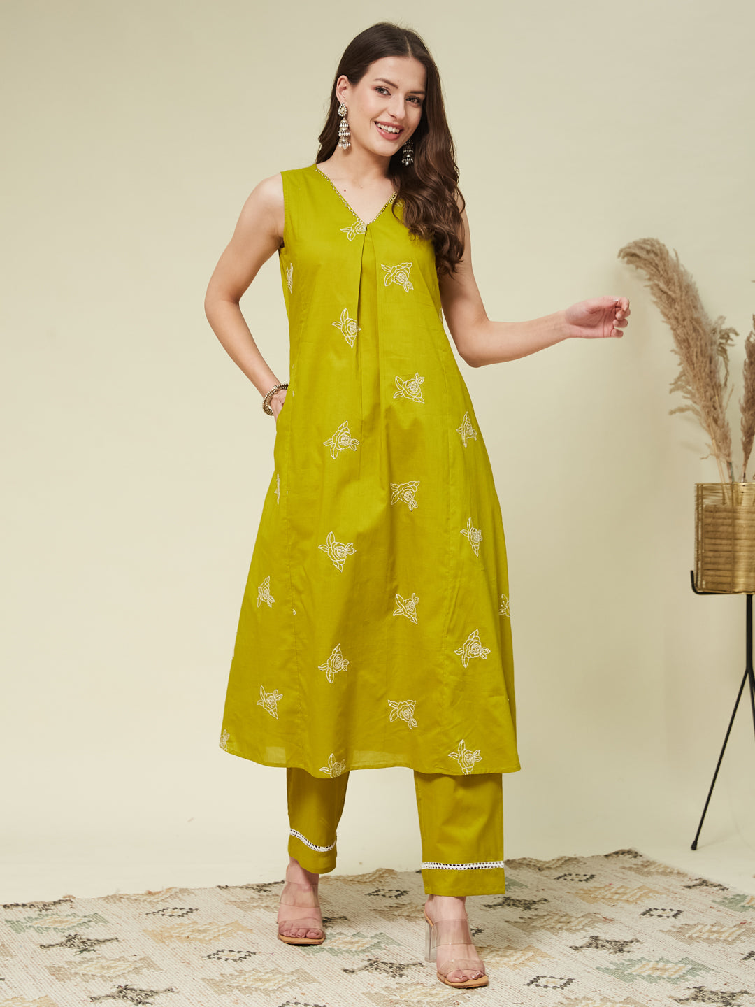 A woman wearing a sleeveless orange top with floral embroidery and matching pants, standing against a neutral background. Pista Embroidered Co Ord Set for Women | Colors of Earth