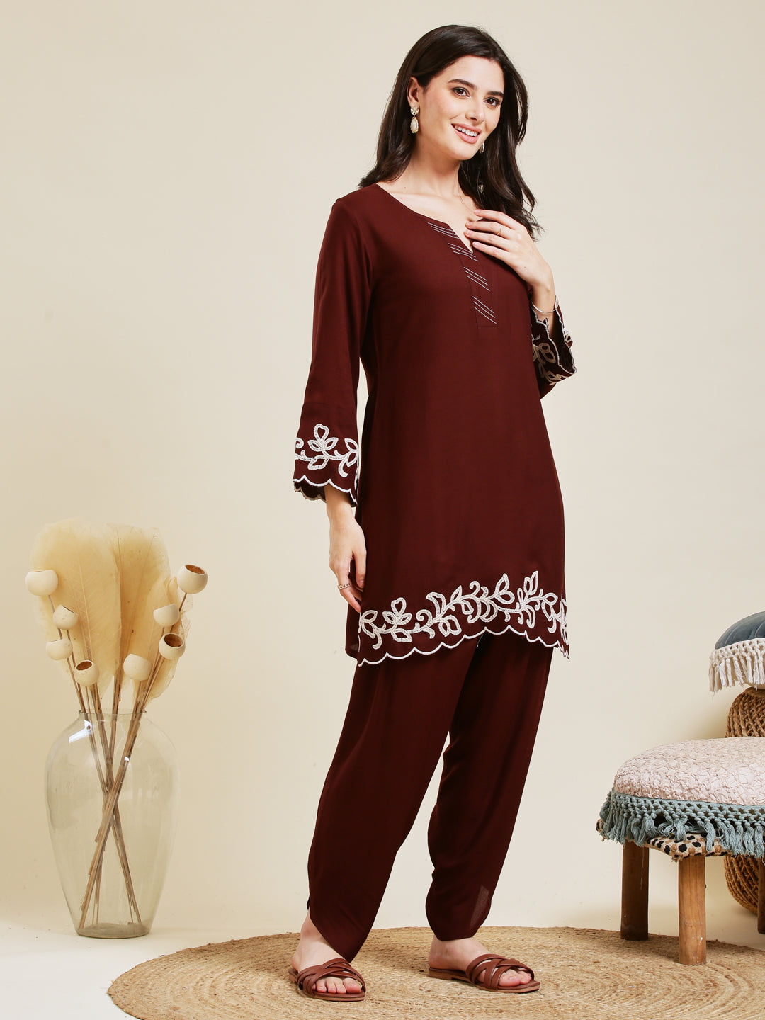 Woman wearing a maroon embroidered outfit standing in a minimalistic room. Coffee Rayon Embroidered Co-ord Set for Women
