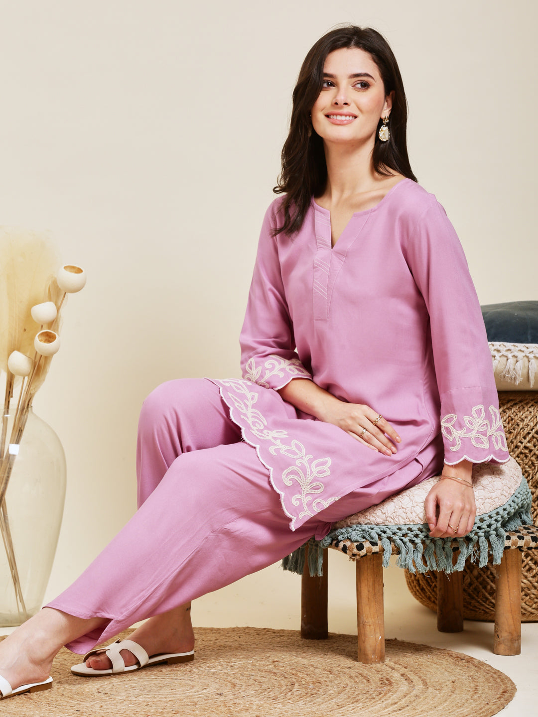 Woman wearing a pink outfit with white embroidery sitting on a stool. Pink Rayon Embroidered Co-ord Set for Women