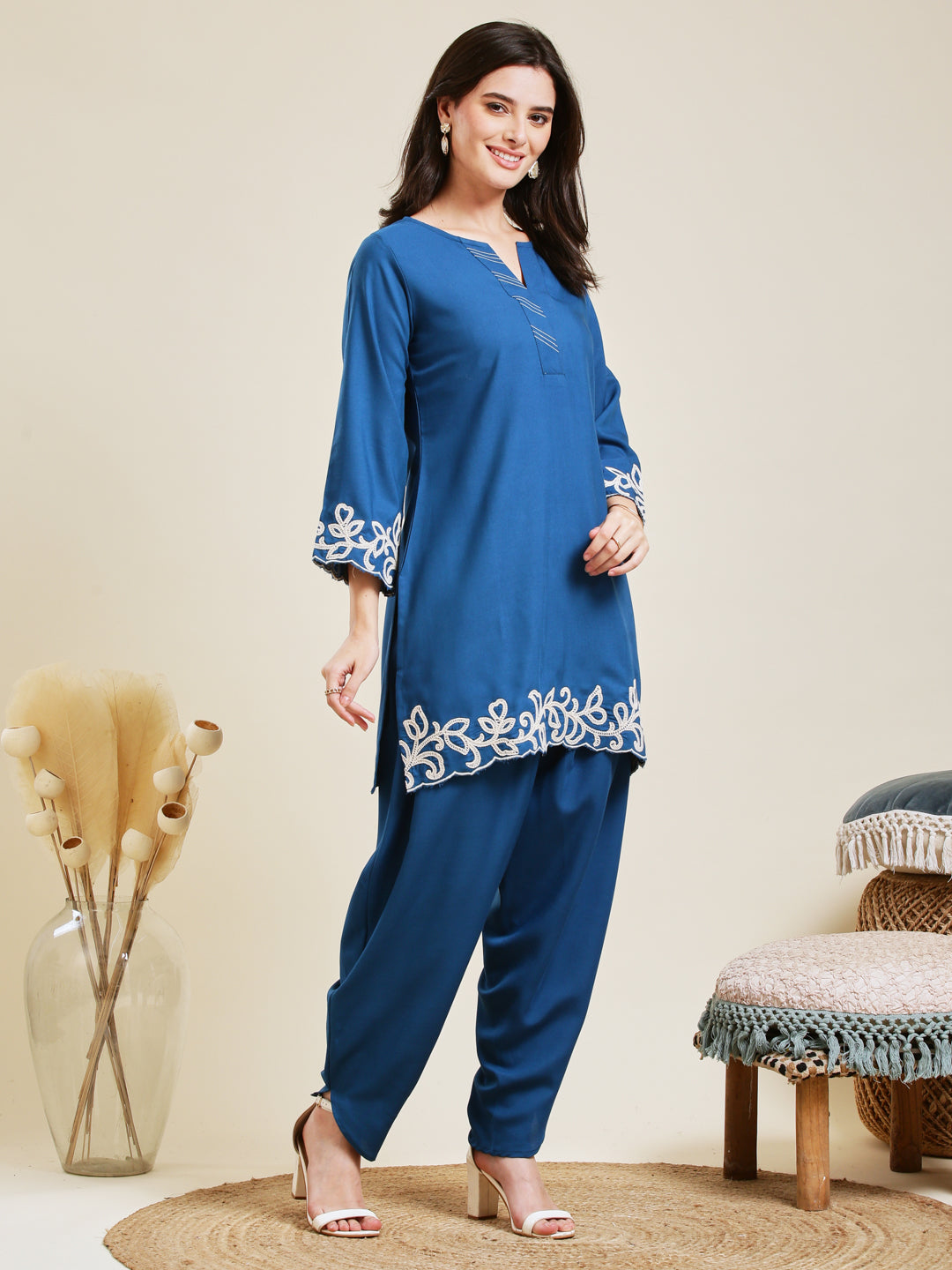 Woman wearing a blue outfit with white embroidery in a minimalistic setting Teal Blue Rayon Embroidered Co-ord Set for Women
